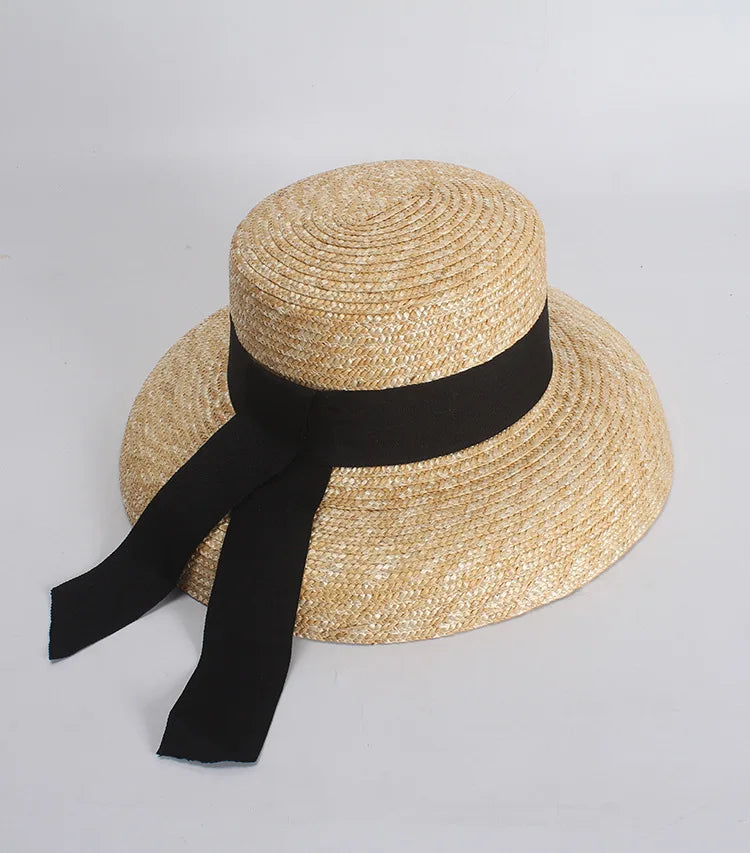 Elegant natural straw boater hat with a wide brim and a black ribbon band with two trailing ribbons.