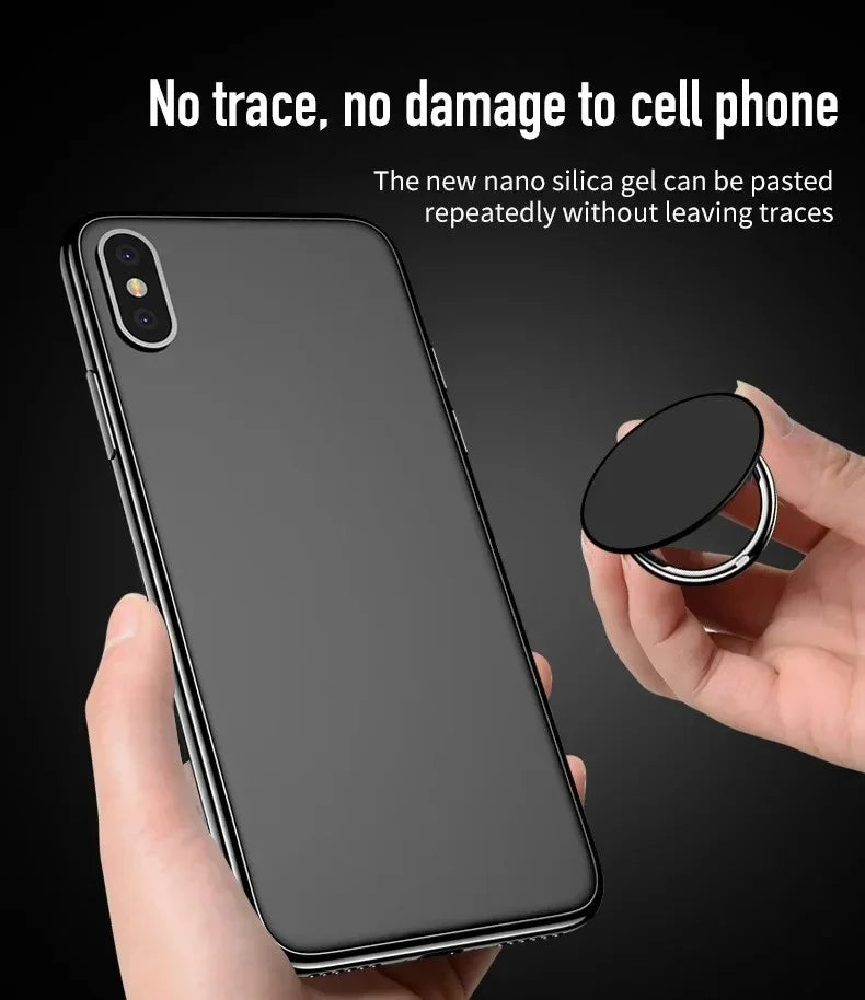 A hand holding a smartphone and a circular, black, foldable metal phone ring grip with a residue-free adhesive backing.