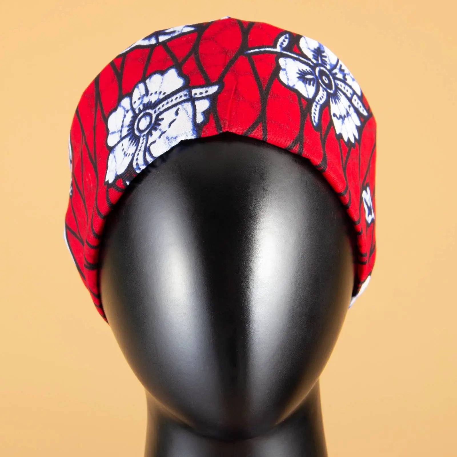 Red headband with a white floral print and black lattice pattern on a black mannequin head.