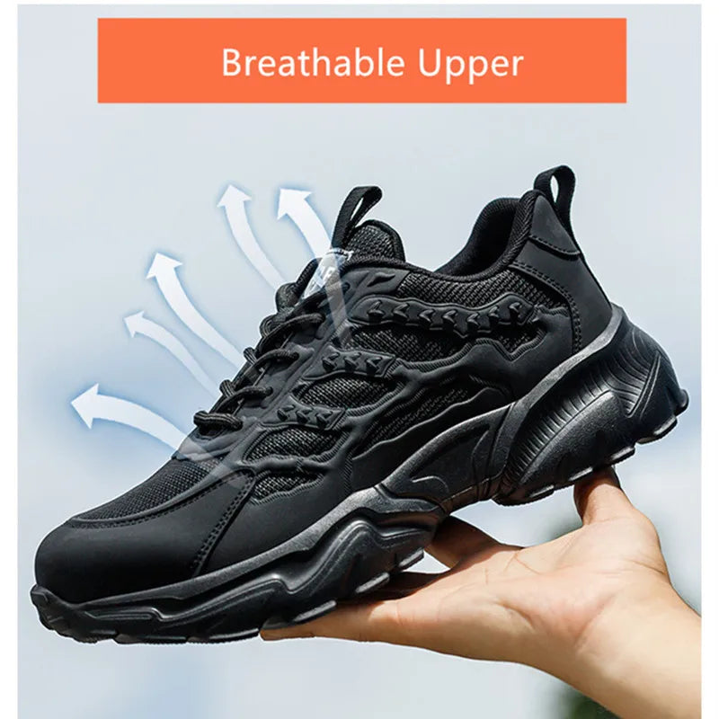 Black safety work sneaker held in hand, featuring a breathable mesh upper, lace-up front, and chunky treaded sole.