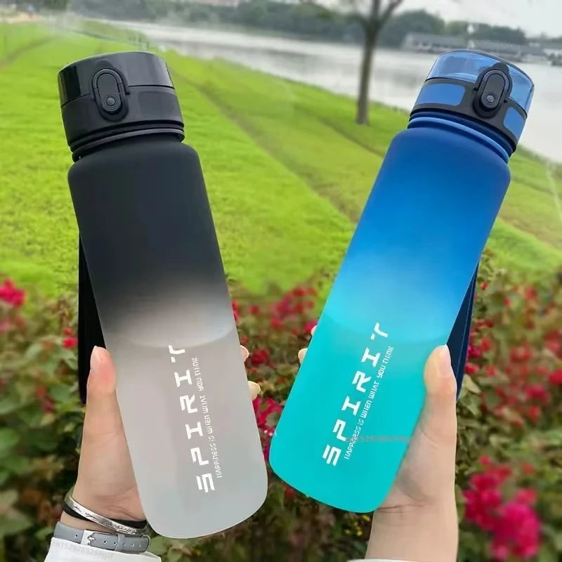 Two ombre-coloured sports water bottles with flip lids, one black-to-clear and one blue-to-teal, labelled "SPIRIT".