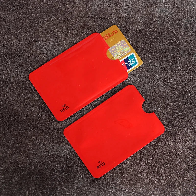 Two red RFID-blocking card sleeves made of thin, smooth material, one holding a gold credit card.