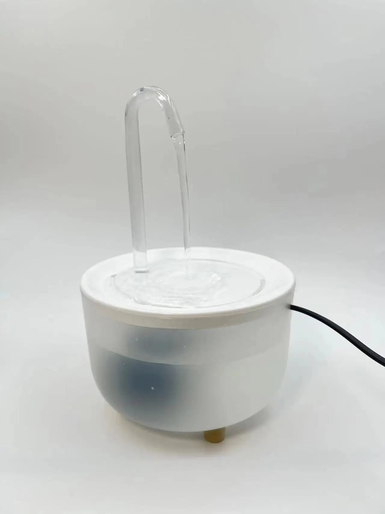 White, cylindrical electric pet water fountain with a clear arched spout and water flowing into a basin.