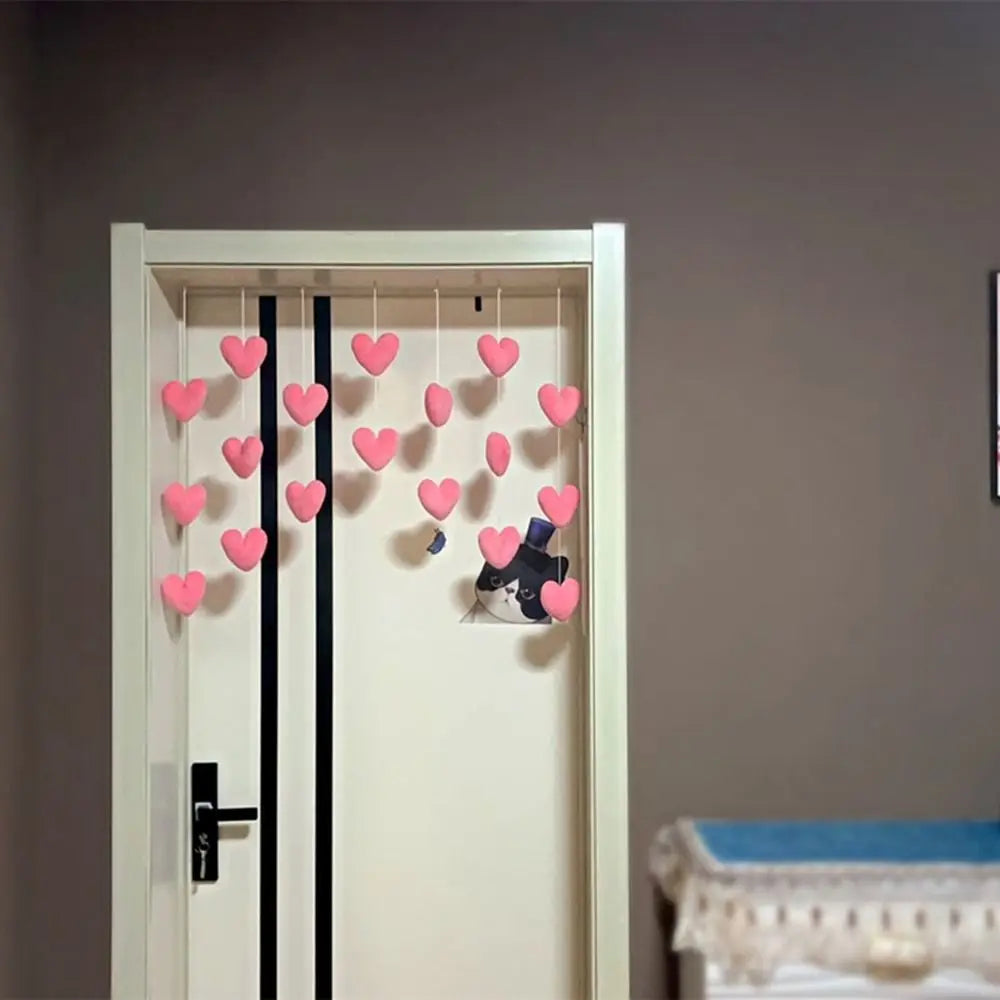 Pink felt heart ornaments hanging on white strings, suspended in a doorway for decorative bedroom style.