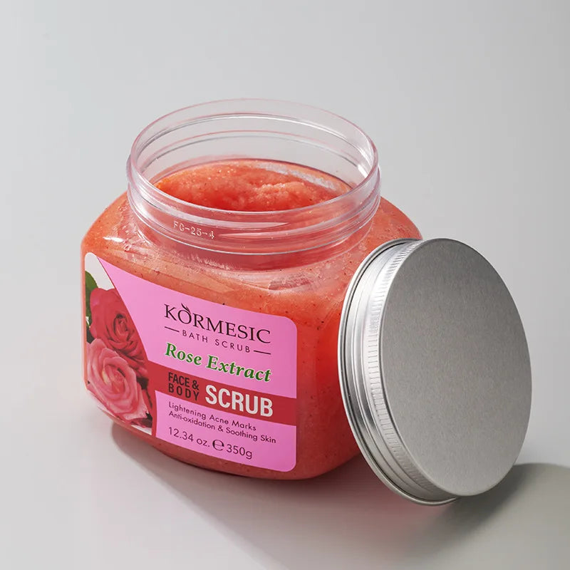 Open jar of pink rose extract face and body exfoliating scrub with a silver metal lid on a plain background.