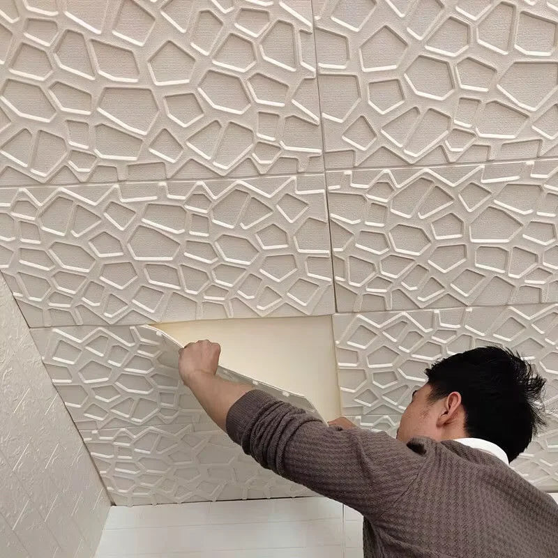 A person installing off-white, 3D self-adhesive wall tiles featuring a modern, abstract geometric lattice pattern.