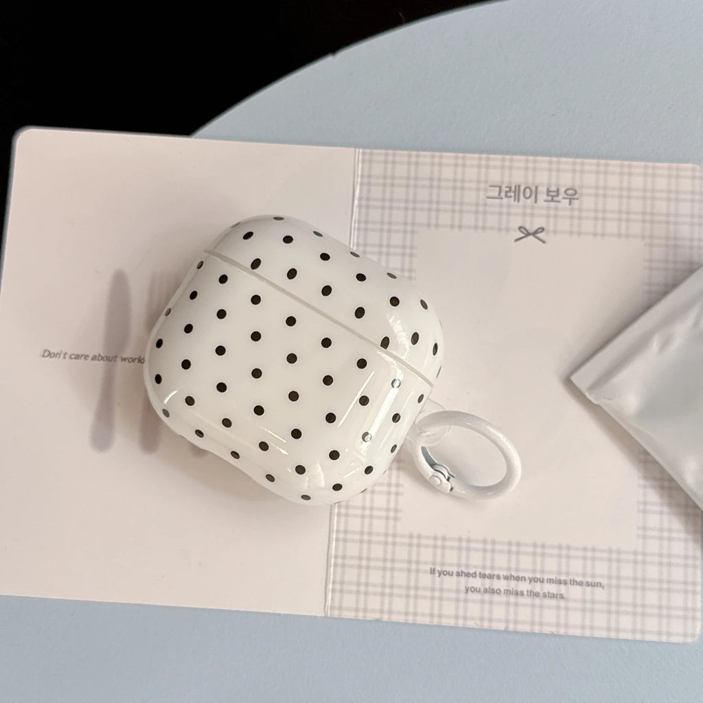 White and black polka dot glossy hard-shell case for AirPods, including a white ring keyring attachment.