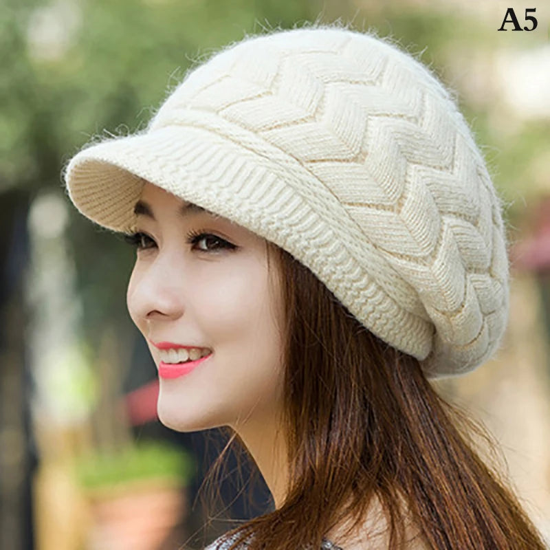 Cream-coloured thermal knitted cap with a peak and chevron pattern, worn by a woman.