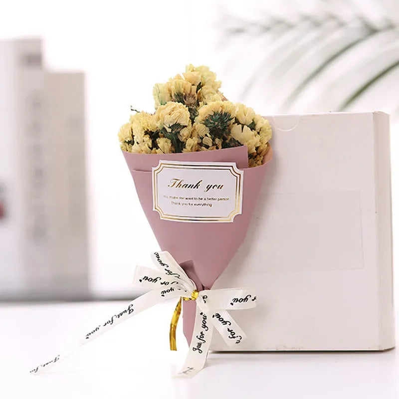 A small bouquet of dried yellow flowers in a dusty pink paper wrap, tied with a ribbon labelled "Just for you".