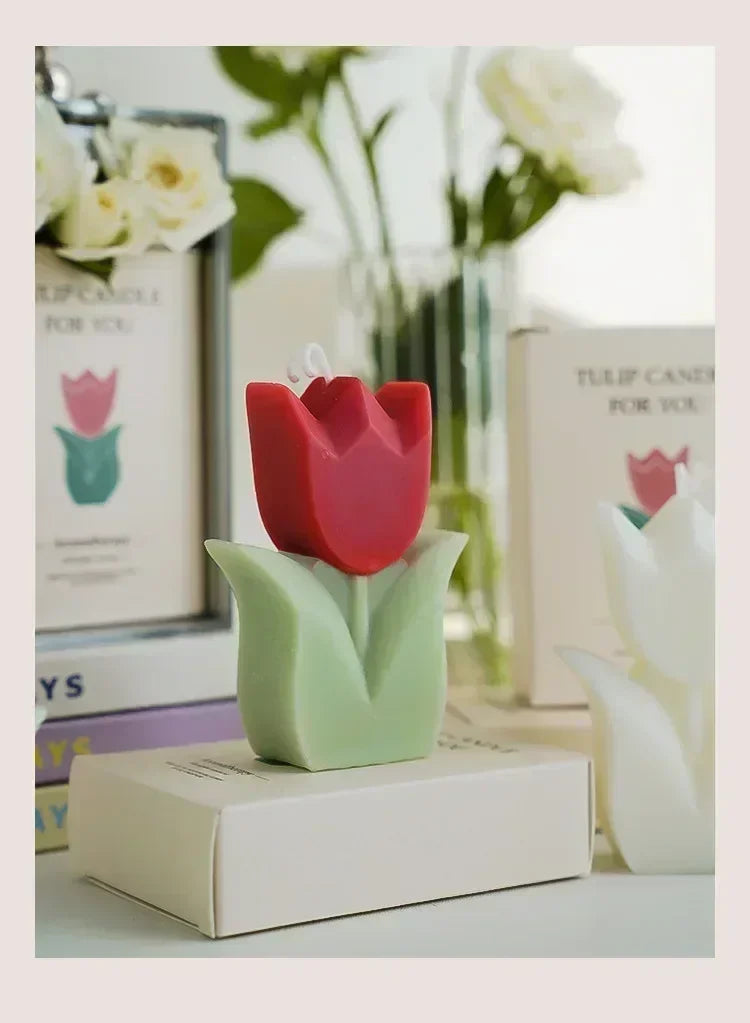 Decorative red and green tulip-shaped wax candle standing on a white box.