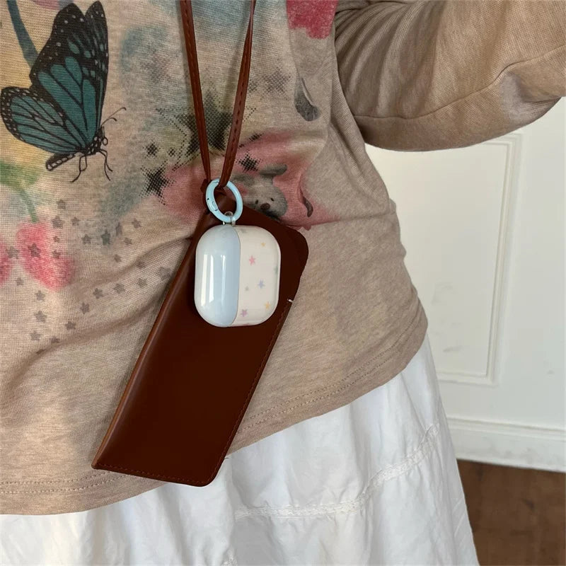 Blue and white star-patterned AirPods Pro case with a brown leather lanyard and light blue ring attachment.