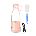 Portable light pink personal blender with cleaning brush and USB charging cable on a white background.