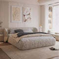 Modern low-profile bed frame in cream textured fabric with a wrap-around cushioned headboard in a minimalist bedroom.