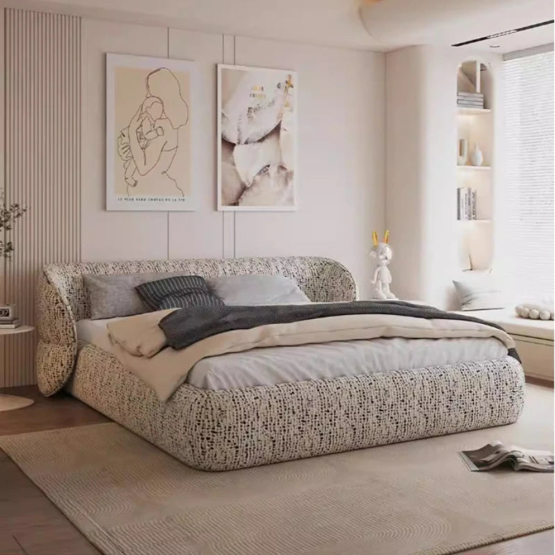 Modern low-profile bed frame in cream textured fabric with a wrap-around cushioned headboard in a minimalist bedroom.
