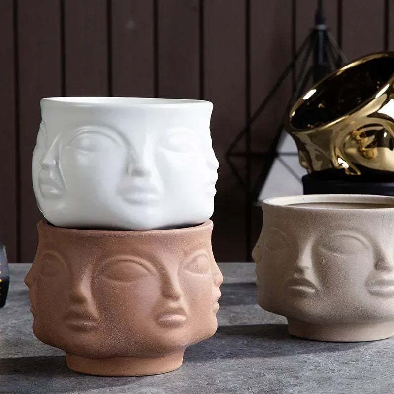 White, terracotta, and stone-effect ceramic plant pots featuring a sculptural, multi-faced abstract design.