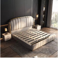 Minimalist cream upholstered bed frame with gold trim, quilted detailing, and a slatted base in a modern bedroom.