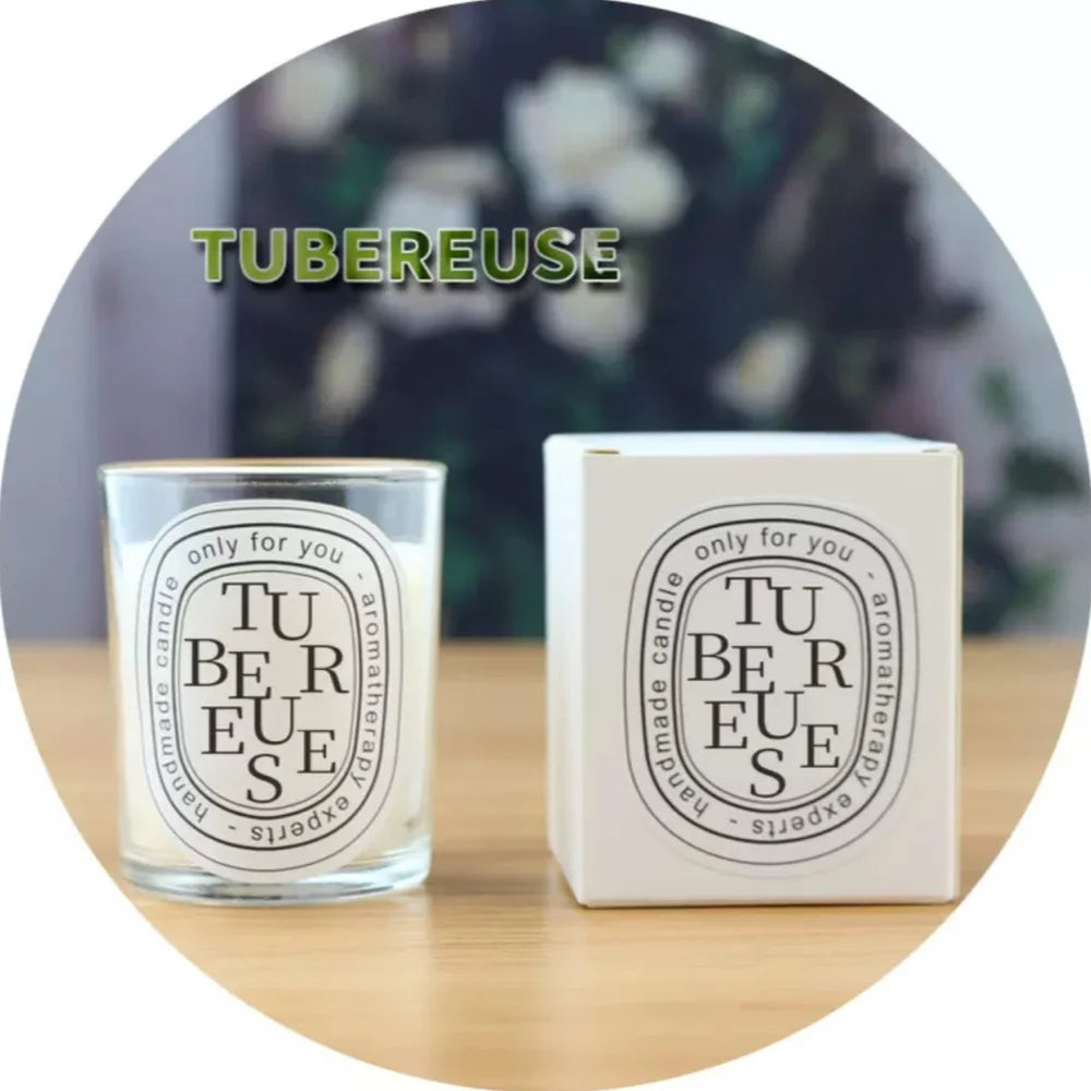 A scented tuberose candle in a clear glass jar with a matching white box, both featuring elegant black oval labels.