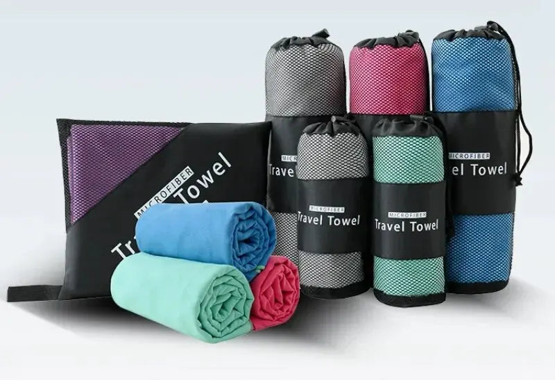 A set of colourful rolled microfiber travel towels, some packed in mesh carry pouches, in various sizes and colours.