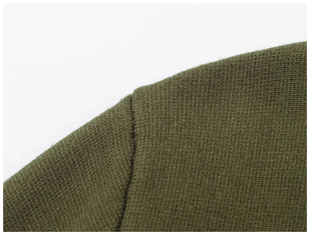 Close-up of olive green knitted fabric showing the shoulder seam and textured stitch pattern.