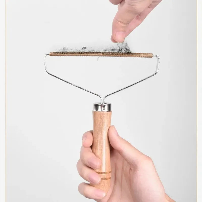 Handheld fabric lint remover with a wooden handle and copper scraping edge, shown collecting lint from clothing.