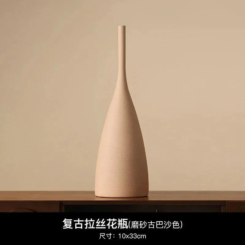 Tall, minimalist beige ceramic vase with a slender neck and textured matte finish in a wabi-sabi style.