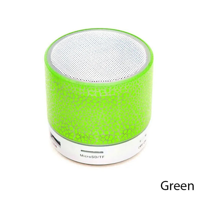 Small, round green LED Bluetooth speaker with a metallic mesh top and USB and MicroSD slots on the white base.