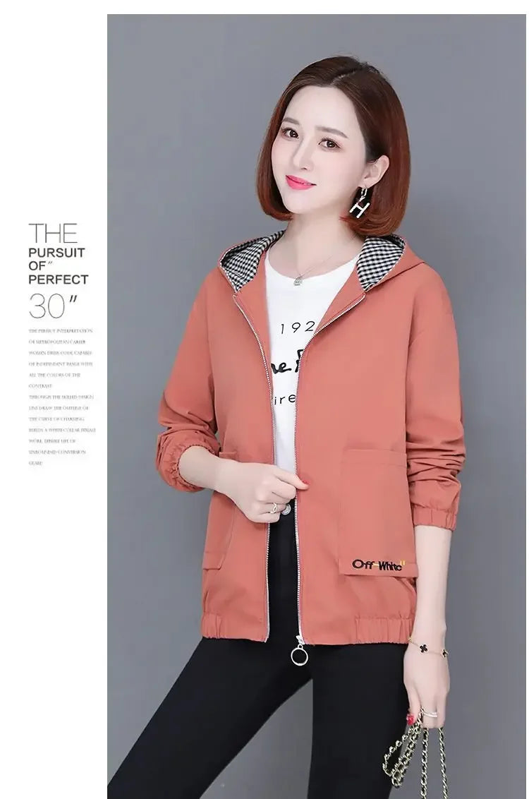 Woman wearing a dusty pink hooded zip-up jacket with a black and white gingham lining and two front pockets.