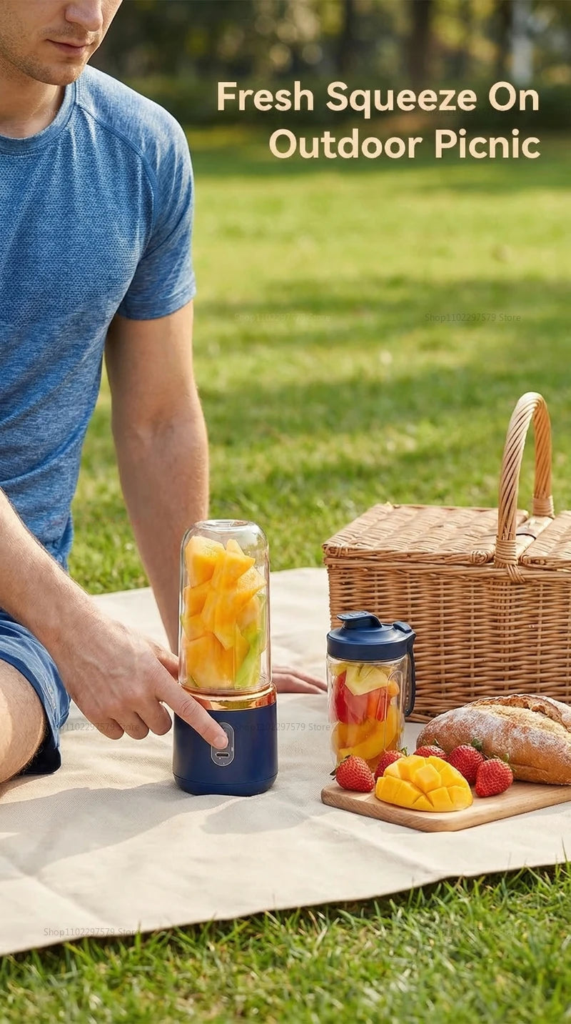 A person using a portable navy blue smoothie blender with a gold rim to blend fruit at an outdoor picnic.