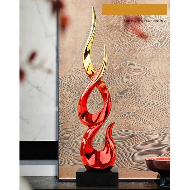 Modern abstract resin ornament featuring a tall, flame-like sculpture in glossy red and gold, set on a black base.