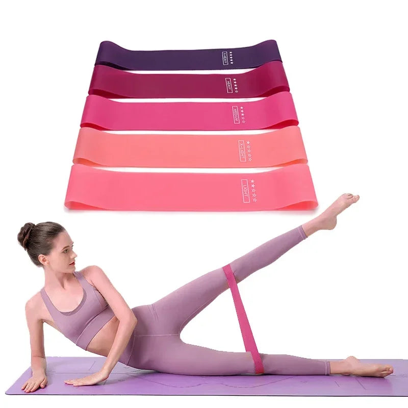 Set of five colourful resistance bands in varying strengths, shown with a person exercising on a purple yoga mat.