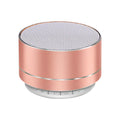 Portable rose gold aluminium Bluetooth speaker with a mesh top, circular design, and control buttons on the base.