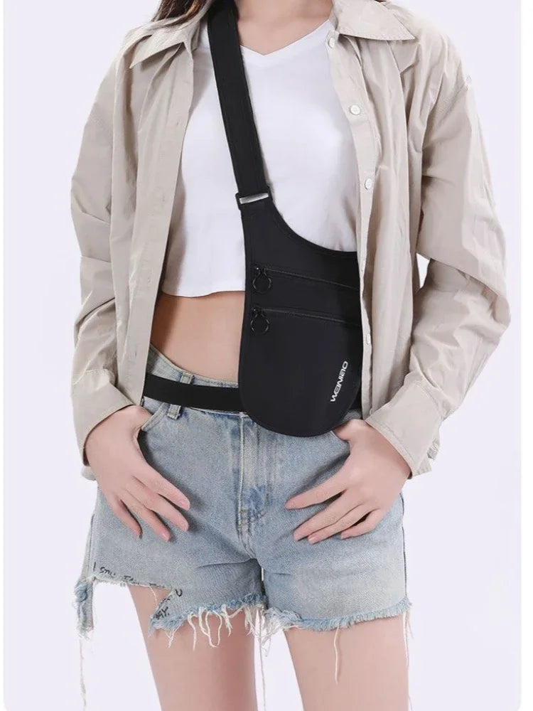 Person wearing a slim black anti-theft crossbody travel pouch with double zip pockets and an adjustable strap.