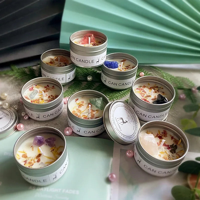 A collection of small silver tin candles, each topped with natural crystals and dried flower petals.