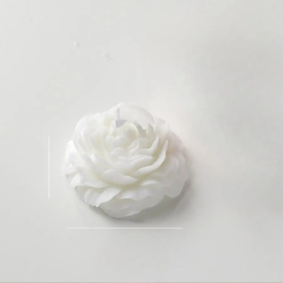 A decorative white candle shaped like a detailed, blooming peony flower on a plain white background.