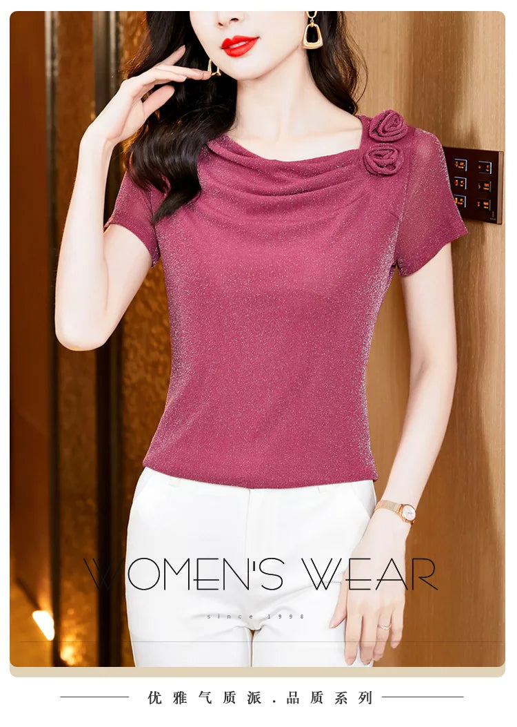 Berry pink shimmer top with cowl neckline, short sleeves, and floral shoulder detail, paired with white trousers.