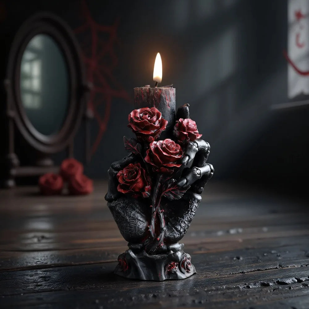 Black skeleton hand pillar candle decorated with detailed red roses, topped with a lit black candle.