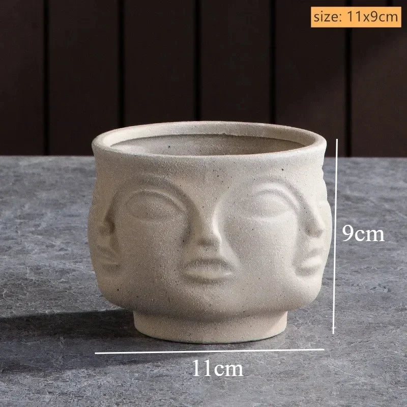 Beige ceramic plant pot with a textured, multi-face sculptural design. Measures 11cm x 9cm. Minimalist artistic style.