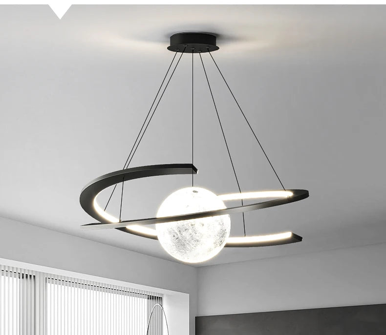 Modern black pendant light featuring a textured, moon-like central orb surrounded by a slim, illuminated ring frame.