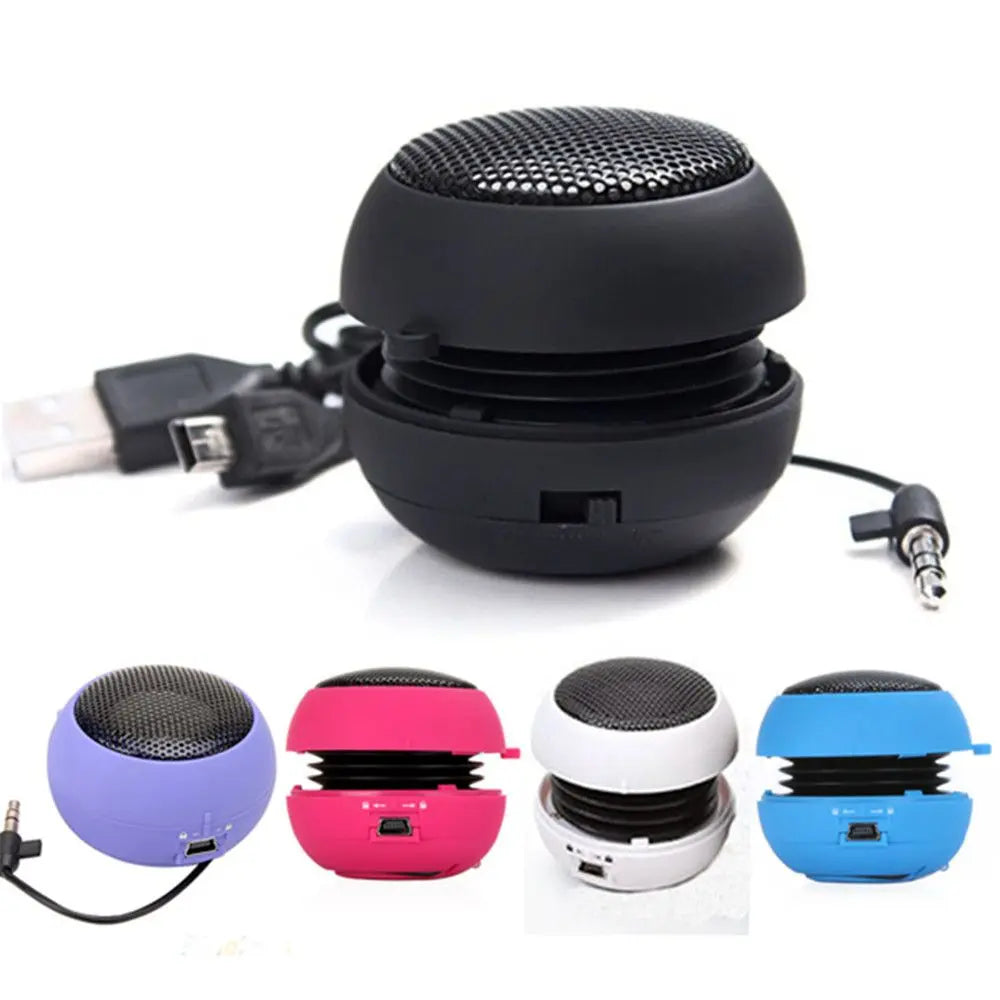 Small, portable, sphere-shaped speakers in various colours, featuring a built-in cable and USB charging port.