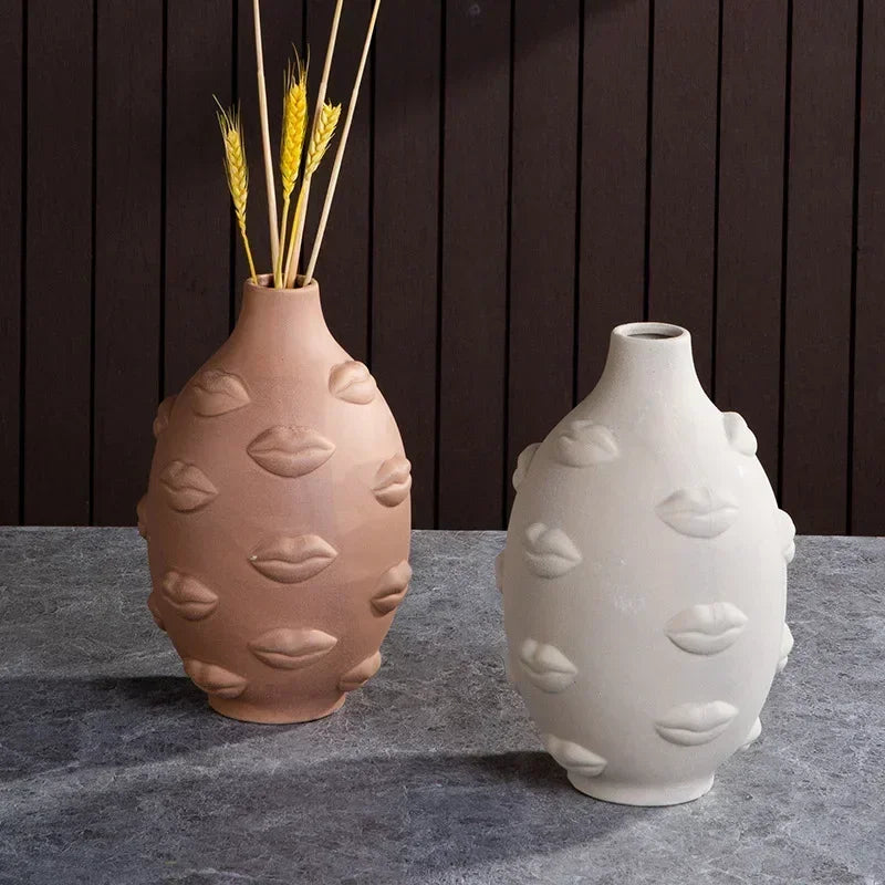 Two oval ceramic vases in terracotta and cream, featuring a textured, embossed lips design on a dark background.