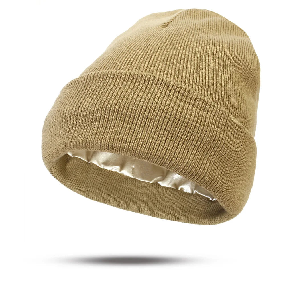 A beige knitted beanie hat with a smooth, satin lining visible on the interior cuff.