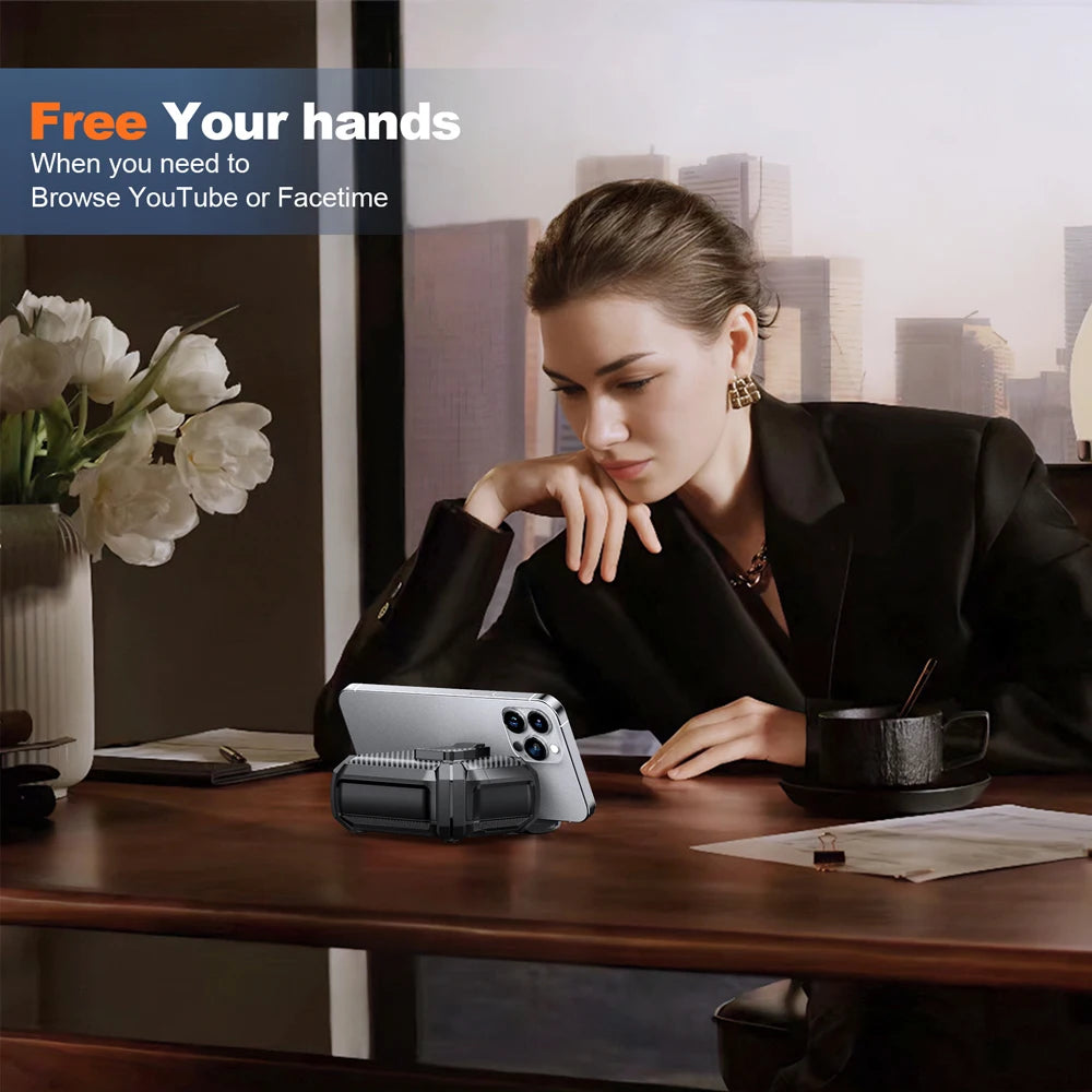 Black, rugged-style hard shell AirPods case acting as a smartphone stand on a desk.