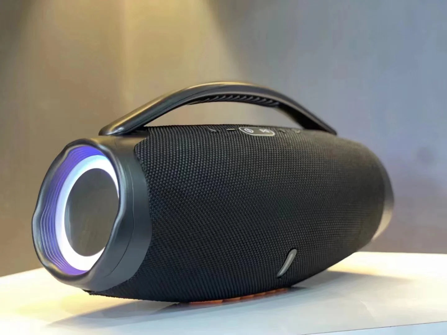 Black portable cylindrical speaker with a carrying handle and glowing circular RGB side lighting.