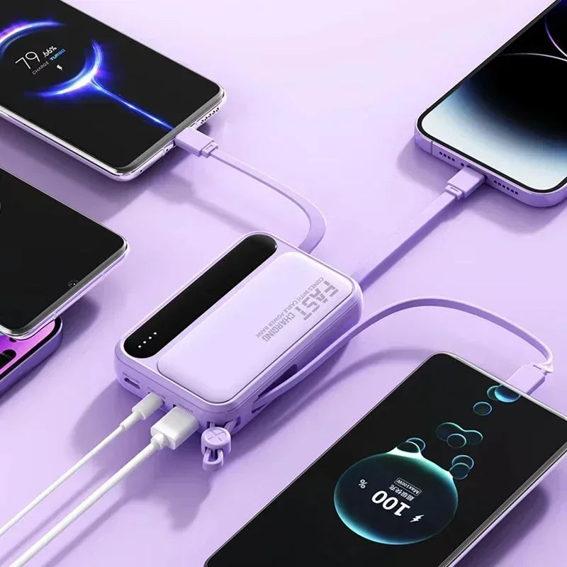 A lilac portable power bank with built-in cables, charging three smartphones simultaneously on a matching lilac surface.