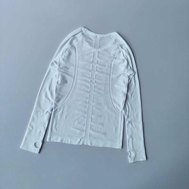 White long-sleeve seamless gym top featuring contouring textures, ribbed cuffs, and integrated thumb holes.