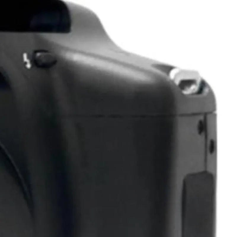 Close-up of a matte black plastic digital camera body showing the top edge, silver strap lug, and flash button.