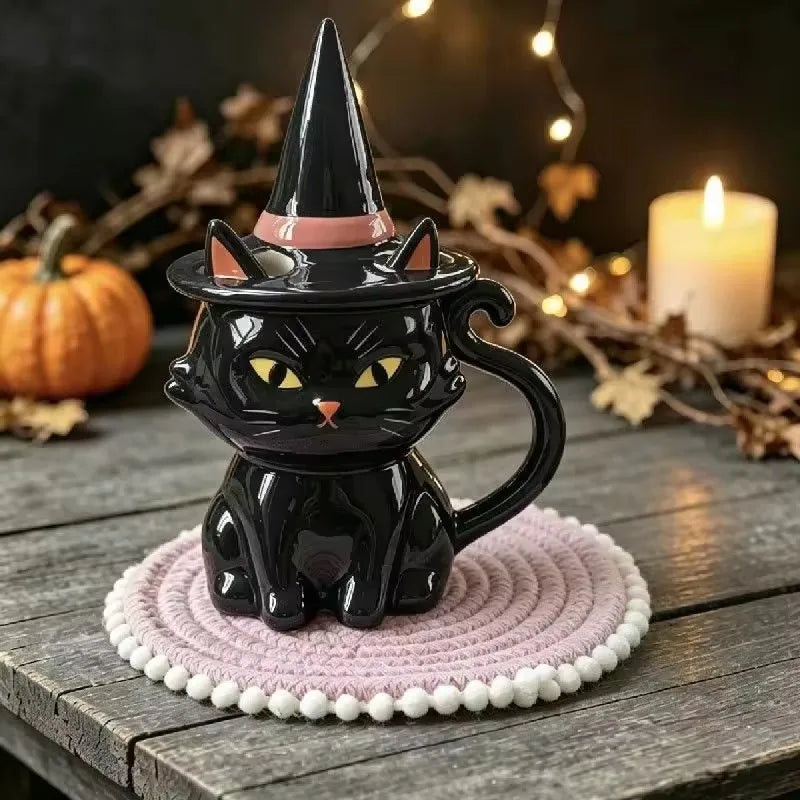 Black ceramic cat mug with yellow eyes, tail handle, and a matching witch hat lid.