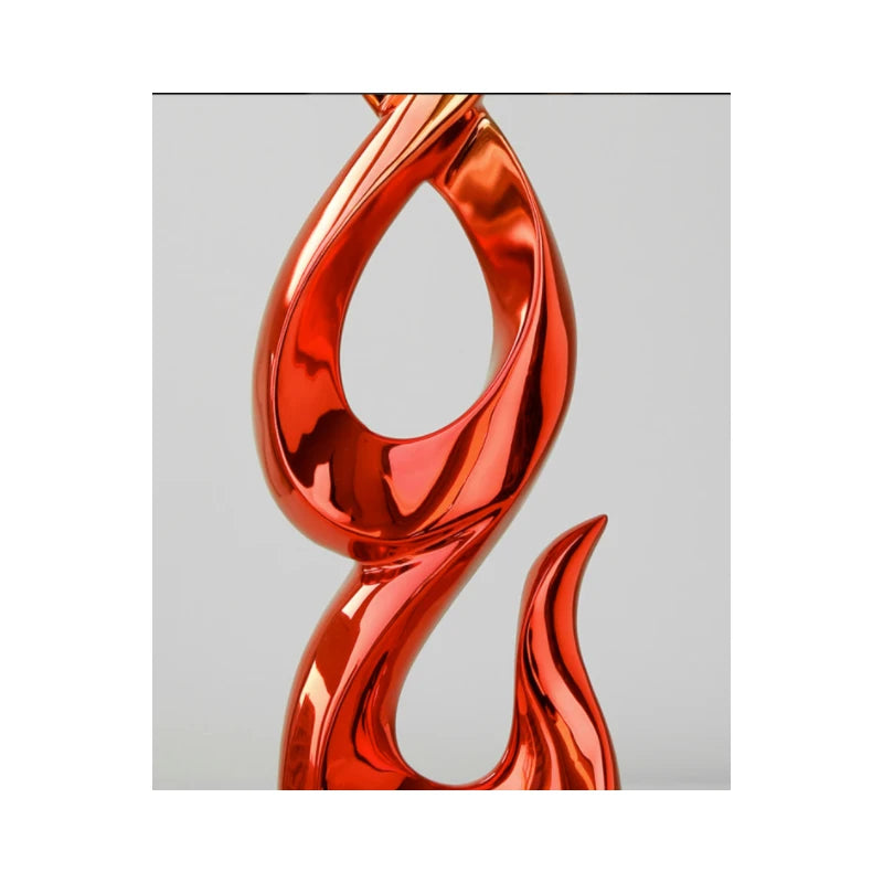 A modern, abstract resin ornament with a high-gloss, reflective metallic red finish and flowing, sculptural curves.
