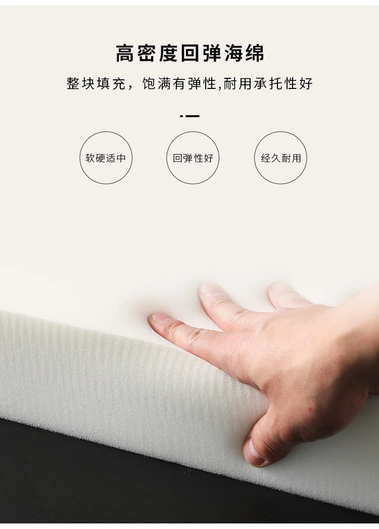 A hand pressing into a thick, cream-coloured block of high-density, resilient foam padding.