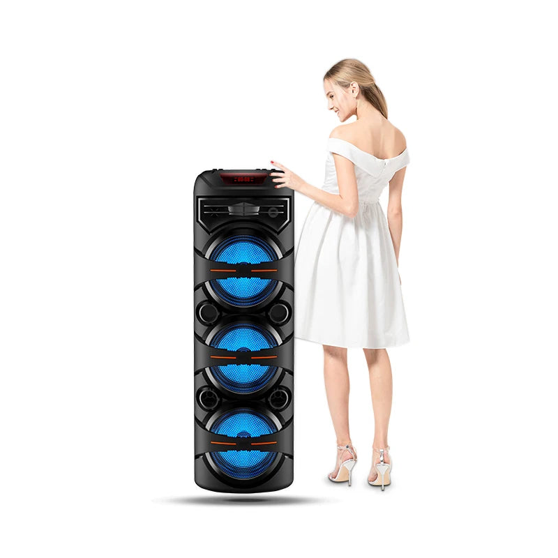 A tall black portable party speaker with three glowing blue circular speakers, standing next to a woman in a white dress.